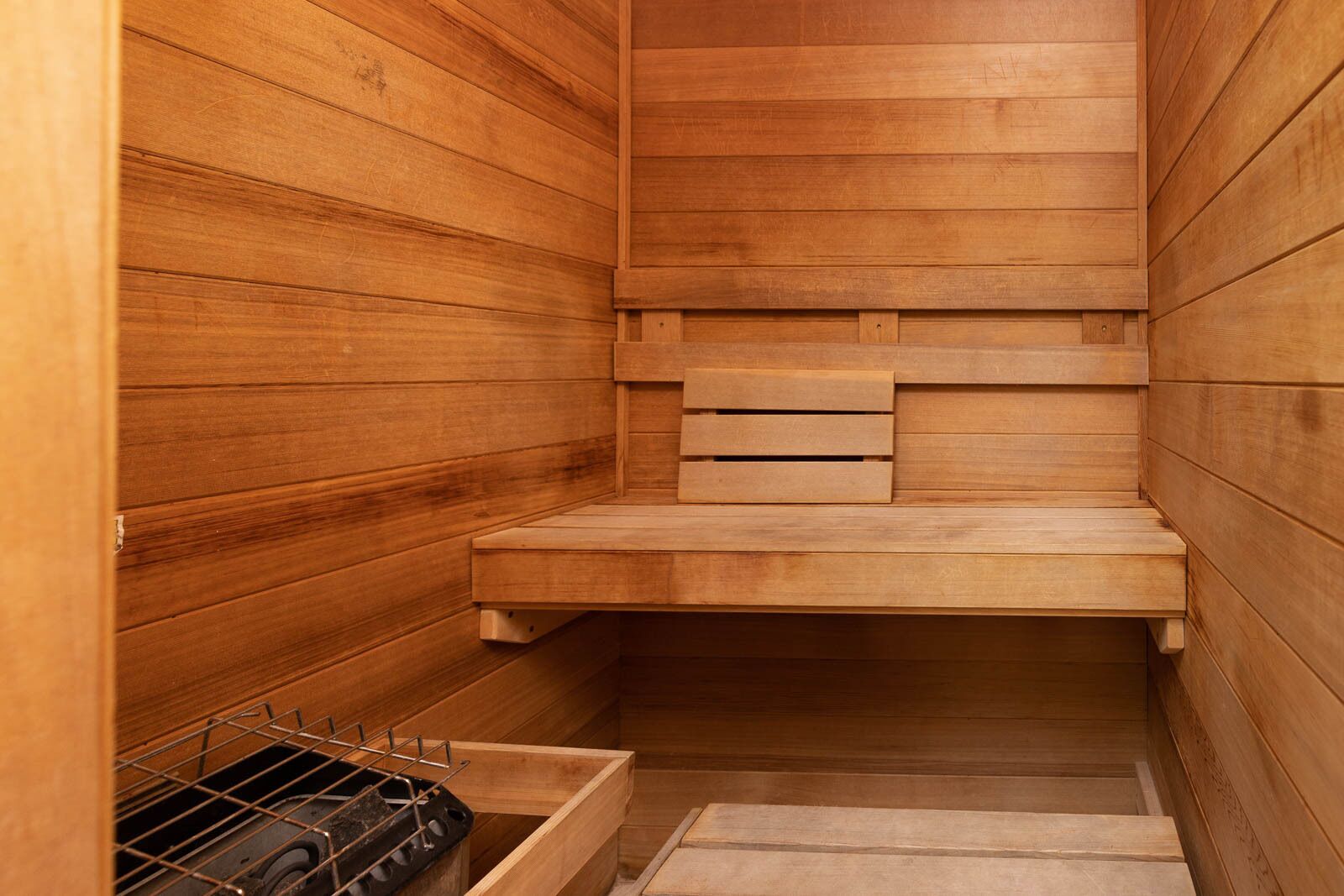 Un sauna en bois avec un banc, une étagère et un porte-serviettes en métal.