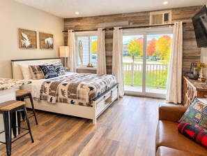 Une chambre à coucher comprenant un lit, un bureau, une chaise, un canapé et un balcon avec vue sur les arbres.