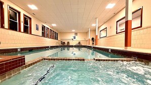 Una piscina con varias pistas, paredes de azulejos e iluminación empotrada en el techo.