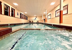 A swimming pool with multiple lanes, tiled walls, and a ceiling with recessed lighting.