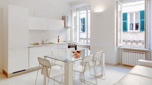 A modern kitchen with white cabinets, a glass dining table, and chairs. There is a window with blue shutters and a view of the outside. - Bright apartment that can accommodate up to 2 people on two floors, located in a renovated period building in the heart of the historic city centre, in a completely pedestrian area just a few steps from the cathedral. The apartment, with a modern and ref (Sarzana)