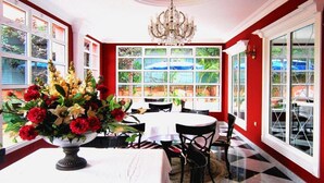 Un comedor con candelabro, una mesa con un florero y vistas al exterior a través de amplios ventanales.