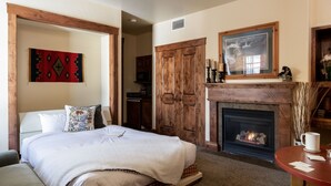 A bedroom with a bed, a fireplace, a dining table, and a hallway leading to a kitchen. - Outpost: Grand View 2810 - AC and Close to town! (Jackson)