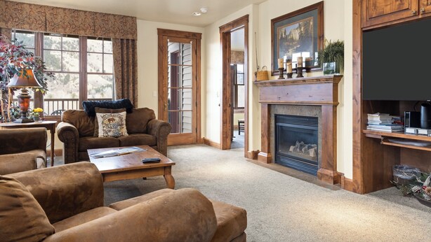 A living room with a fireplace, wooden furniture, and a large window. - Outpost: Grand View 2810 - AC and Close to town! (Jackson)