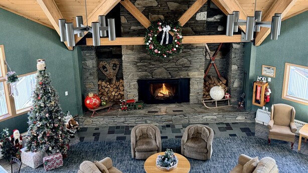 Una sala de estar acogedora con chimenea de piedra, un árbol de Navidad y asientos cómodos.