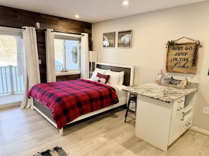 Een slaapkamer met een bed, een wastafelmeubel en een raam met gordijnen.