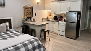 Una cocina moderna con armarios blancos, un refrigerador de acero inoxidable y una pequeña isla con taburetes.