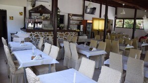 Un restaurant amb tovallons blancs, cadires de vimet i una paret de pedra.