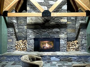 Une cheminée en pierre avec un feu de bois, un tapis tissé et un mur en pierre.