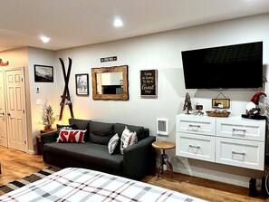 Una sala de estar con un sofá, una televisión, una chimenea y un espejo en la pared.