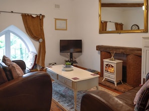 A living room with a sofa, a television, a fireplace, and a large mirror. - 1 bedroom accommodation in Rigg, near Gretna Green (Rigg, near Gretna Green)