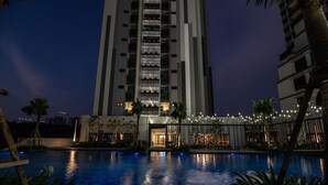 A modern high-rise hotel with a swimming pool in the foreground. - Ramada by Wyndham Meridin Johor Bahru (Iskandar Puteri)