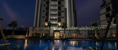 A modern high-rise hotel with a swimming pool in the foreground.