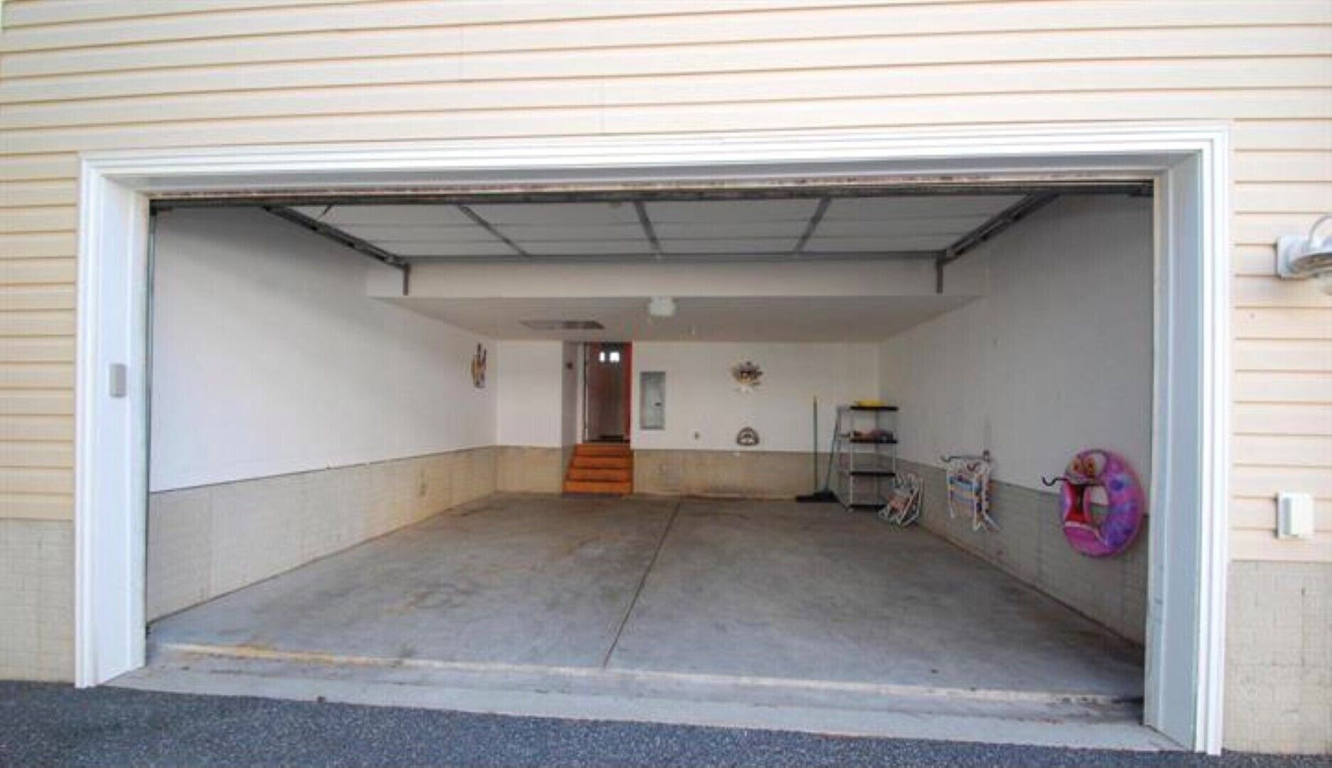 Ett garage med ett betonggolv, en metalldörr och en liten trappa som leder till en dörr längst in.