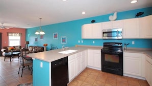 Una cocina con armarios blancos, una estufa negra y una pared azul.