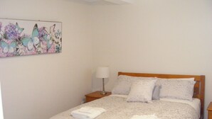 A neatly made bed with a patterned bedspread and two folded towels on the side.
