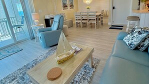 Un soggiorno moderno con un divano, un tavolino da caffè e un'area pranzo con sedie e un lampadario.