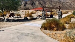 A desert landscape with a sign for the Bear Creek Trail.