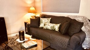 A living room with a dark brown sofa, a glass coffee table, a lamp, and a patterned rug.
