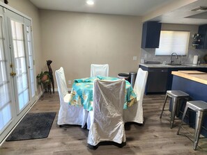 Cozinha compacta com área de refeições, destacando uma mesa com cadeiras, pia e janela com persianas.