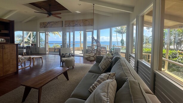 A spacious living area with a large sofa, a wooden table, and a ceiling fan. - OCEANFRONT DUPLEX, with POOL, SAUNA and steps from BEACH (Hilo)