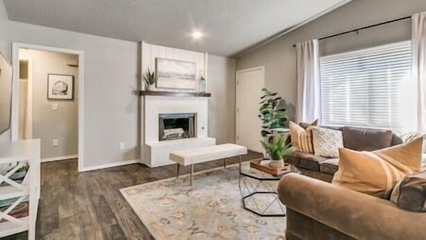 A living room with a fireplace, a sofa, a coffee table, and a large window with blinds.