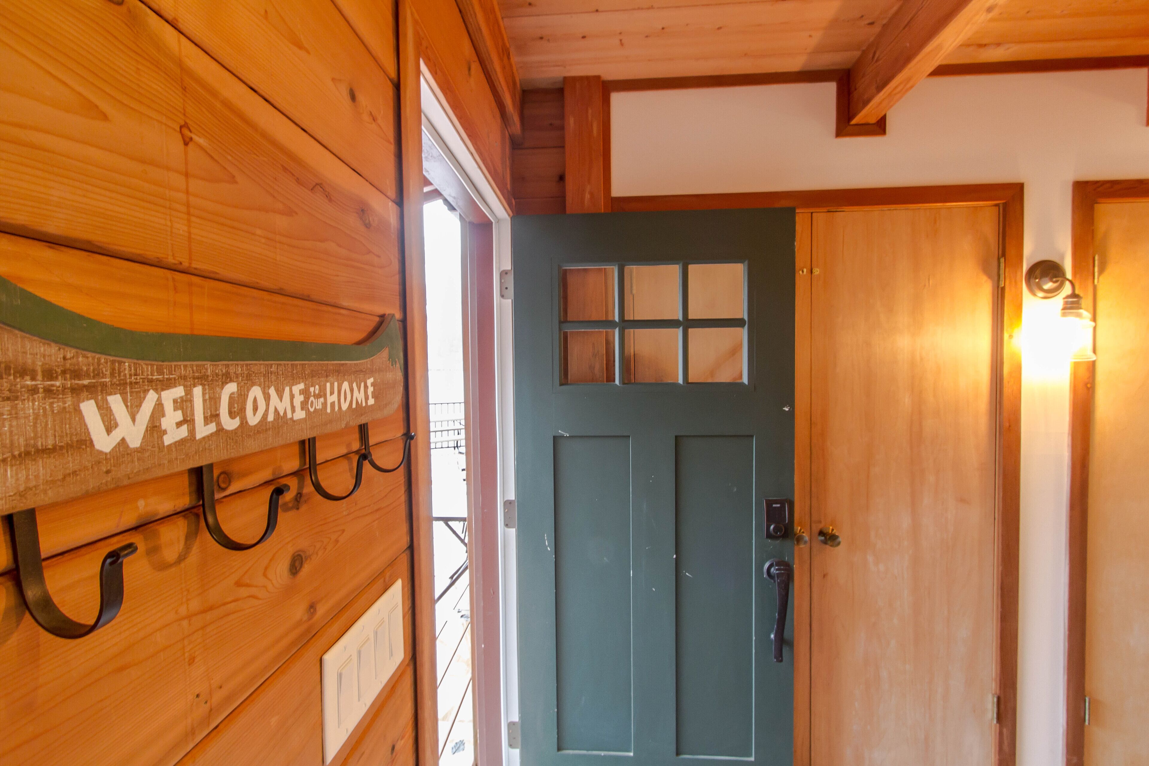 Un muro esterno in legno con un cartello che riporta 'Welcome Home' e una porta con una finestra.