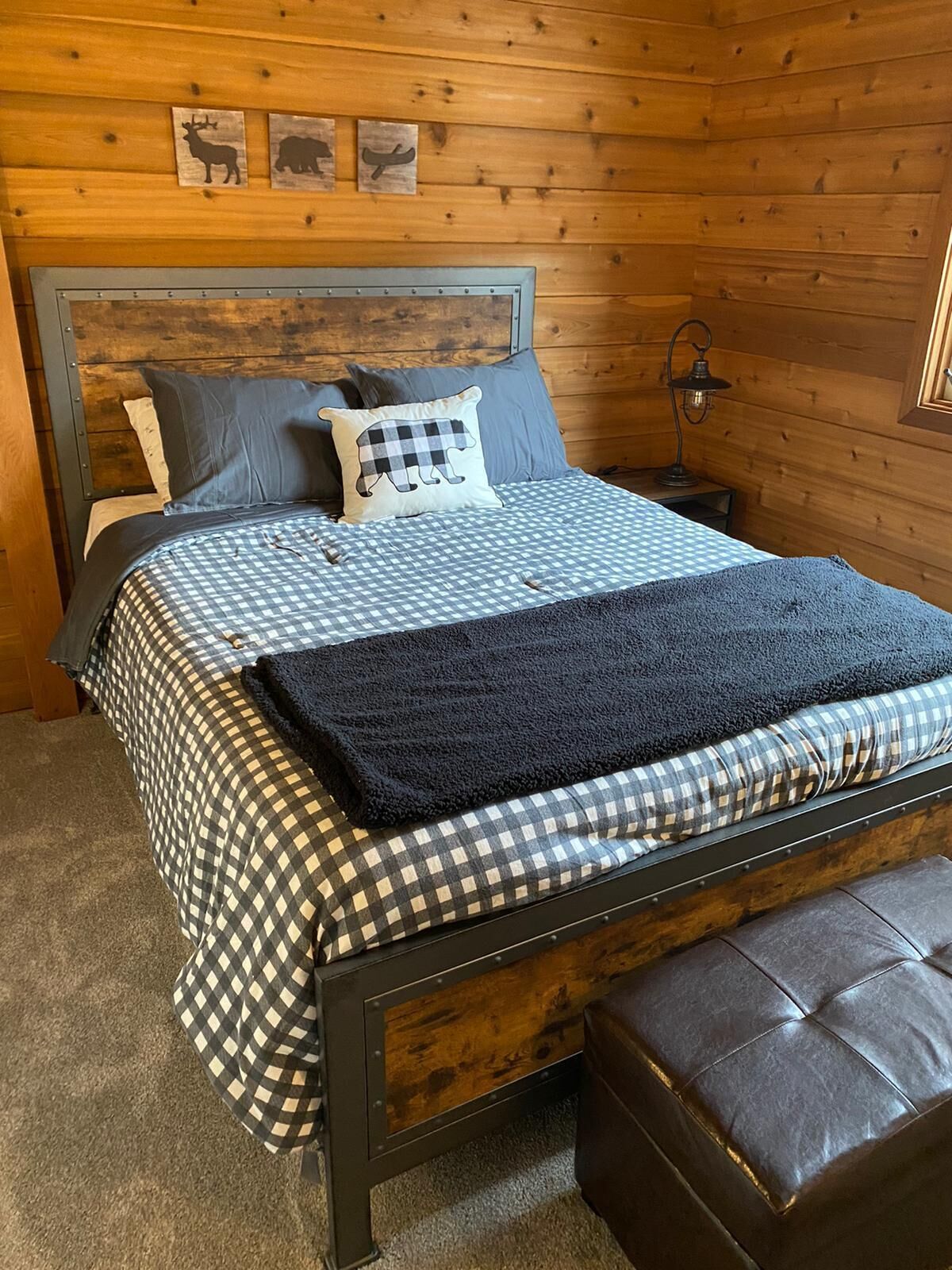 Ett sovrum inrett som en stuga, med en säng, kuddar, en filt och en bänk.