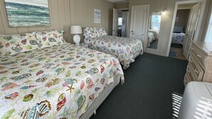 A room with two beds, a ceiling fan, a painting of the ocean, and a dresser. - San Bel - Second row in Garden City Beach (Garden City)