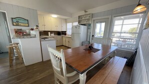A kitchen with a wooden table and bench, white cabinets, and a window with blinds. - San Bel - Second row in Garden City Beach (Garden City)