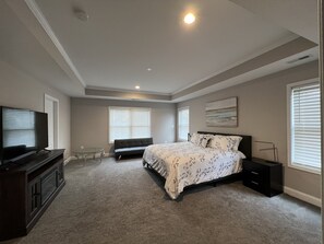A bedroom with a bed, a TV, a dresser, and a window.