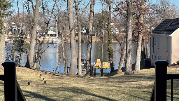 A lakeside view with a dock, trees, and houses in the background. - NEW 5 Bedroom Home with  Pier by Water (Riviera Beach)