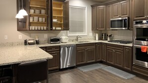A modern kitchen with dark wood cabinets, stainless steel appliances, and a granite countertop. - NEW 5 Bedroom Home with  Pier by Water (Riviera Beach)