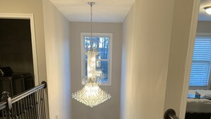 A staircase with a chandelier, a door with a glass panel, and a window with blinds. - NEW 5 Bedroom Home with  Pier by Water (Riviera Beach)