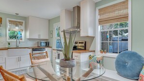 A modern kitchen with white cabinets, a stainless steel oven, and a glass dining table.