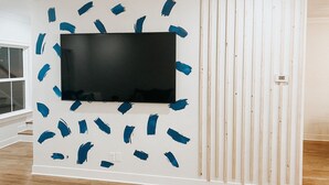 A room with a large flat-screen TV mounted on a white wall, surrounded by blue painter's tape. - Bright stylish home minutes to downtown! New build with HUGE pool/hot tub combo! (Chattanooga)
