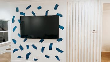 Ein Zimmer mit einem großen Flachbildfernseher, der an einer weißen Wand befestigt ist und von blauem Malerkrepp umgeben ist.