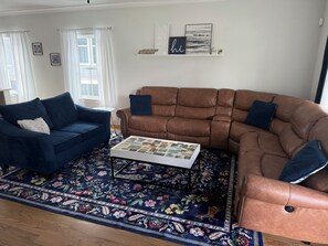 Ein Wohnzimmer mit zwei Sofas, einem Couchtisch und einem gemusterten Teppich.