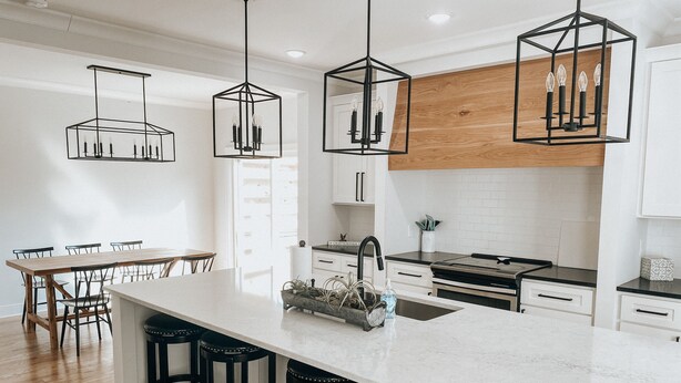 A modern kitchen with a large island, bar stools, pendant lights, and wooden cabinetry. - Bright stylish home minutes to downtown! New build with HUGE pool/hot tub combo! (Chattanooga)