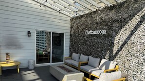A patio with outdoor furniture, a wall with a leafy texture, and a sign reading 'Chattanooga'. - Bright stylish home minutes to downtown! New build with HUGE pool/hot tub combo! (Chattanooga)