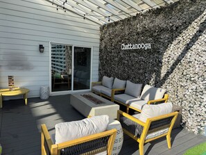 Eine Terrasse mit Gartenmöbeln, eine Wand mit einer belaubten Struktur und ein Schild mit der Aufschrift 'Chattanooga'.