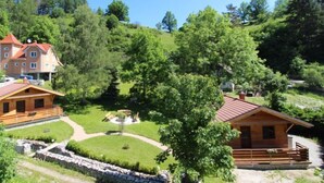 Un chalet comprenant plusieurs cabanes en bois, un jardin central et un grand bâtiment en arrière-plan.