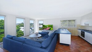 Eine moderne Küche mit einer integrierten Kochinsel, einem blauen Sofa und einem Esstisch.