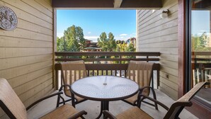A wooden balcony with a round table and four chairs. - Downhill Den! Mountain Views, Private Patios, Outdoor Pool, 4 Hot Tubs, Pickleball Courts! (Steamboat Springs)