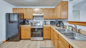 A modern kitchen with wooden cabinets, stainless steel appliances, and a double sink. - Lincoln Apartment w/ Balcony: 2 Mi to Loon Mtn! (Lincoln)