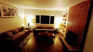 A living room with a sofa, a coffee table, a side table, and a brick wall.