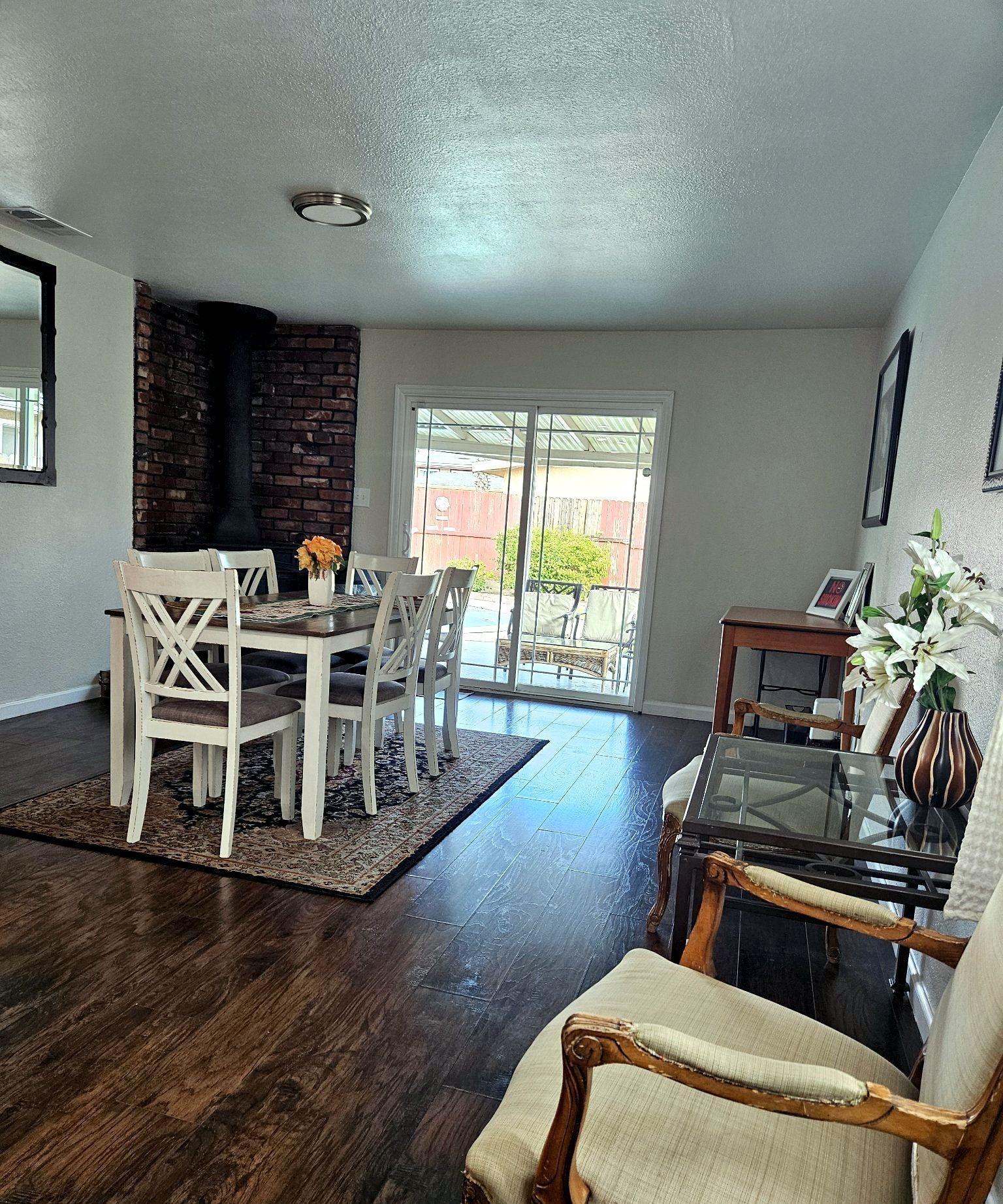 A dining area with a brick wall, a glass door leading outside, and a dark wooden floor.