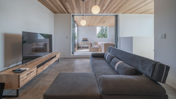 A modern living room with a flat-screen TV, wooden ceiling, and a large gray sofa. - Shimakaji Villa Onna (Onna)