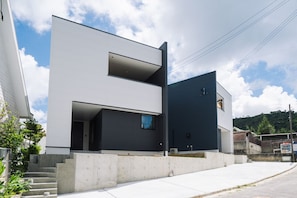 A modern two-story building with a flat roof, large windows, and a concrete base. - Shimakaji Villa Onna (Onna)