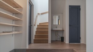 A modern interior with a wooden staircase, a bathroom with a sink and mirror, and a dark door. - Shimakaji Villa Onna (Onna)